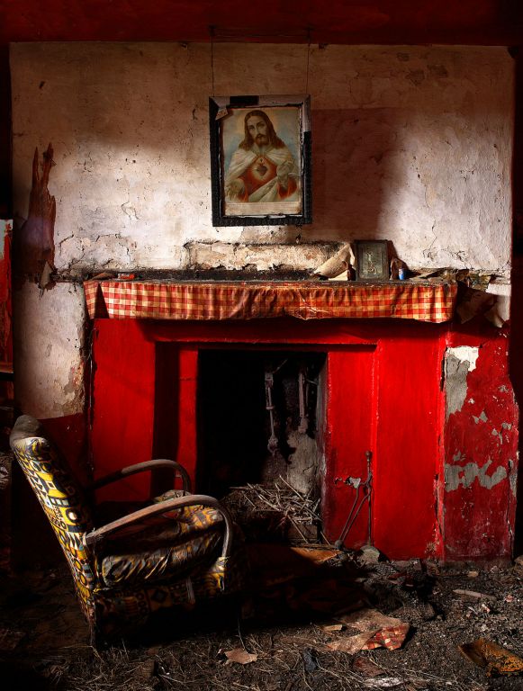 The Sacred Heart hangs over a fireplace, on the mantelpiece is a bottle of pills, a picture of the crucifixion and an Everyready battery. Around the fireside are a set of tongs and a shovel. The Feast of the Sacred Heart is celebrated 19 days after Pentecost. 