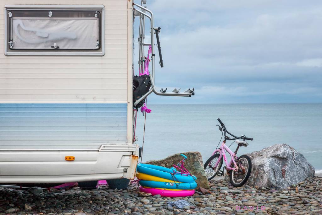 An overcast morning as a childs bicycle and swimming rings have been left outside a campervan overnight on the seafront at Garrettstown, Co. Cork, Ireland. 