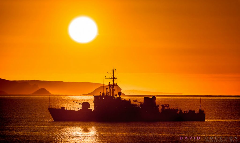 Naval patrol vessel L.É. Orla silhouetted against the rising Sun while at anchor near the Old Head of Kinsale Co. Cork.