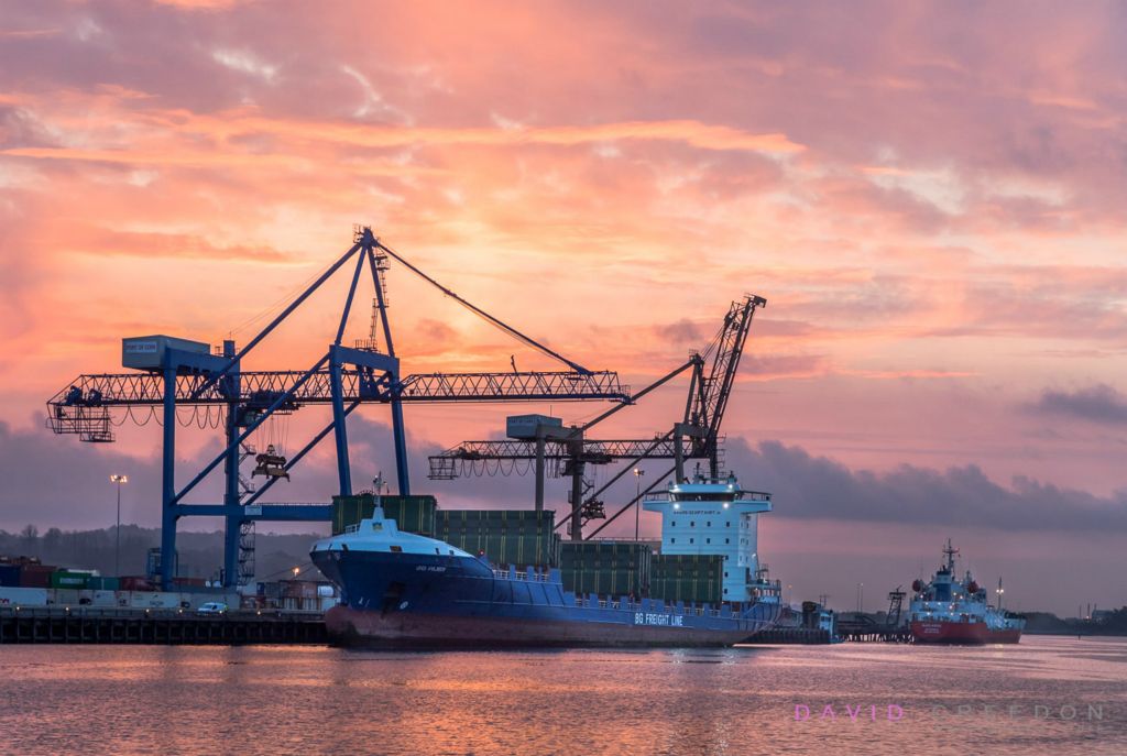 As dawn breaks container vessel BG Ruby offloads a cargo from Rotterdam while the tanker Marianne discharges her load of liquid gas at Tivoli Docks in Cork, Ireland.  