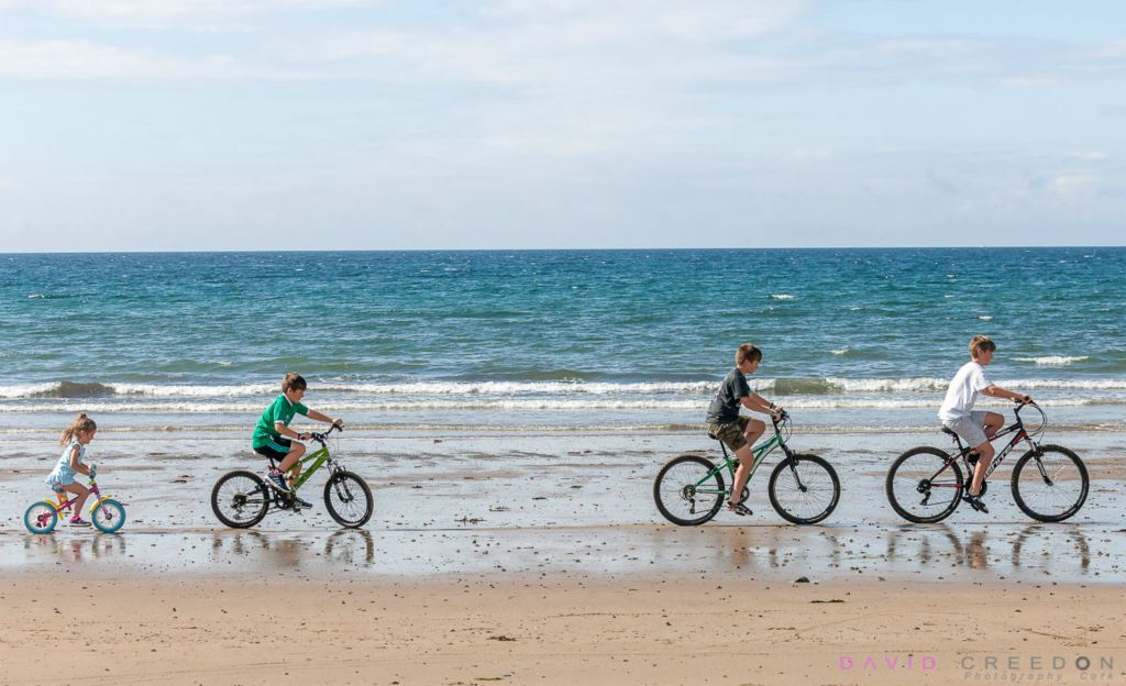 Riding bicycles on the beach on a warm summers morning at Garrylucas, Co. Cork, Ireland. 