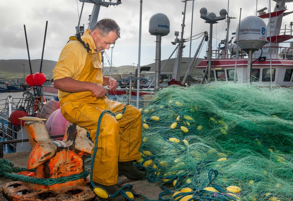 Fisherman Edward Nova from the French trawler Kalicoba mending nets on the quayside in Castletownbere, Co. Cork, Ireland.