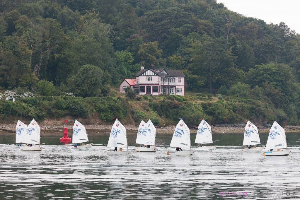 A flotilla of Optimist Dinghies pass Curribinny after leaving the Royal Cork Yacht Club at the start of the Optimist Irish National Championships that are been held in Crosshaven, Co. Cork, Ireland.