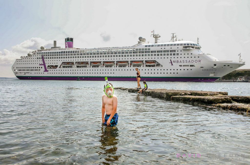 A little boy plays in the sea as the cruise Ship Ambience arrives in Cobh